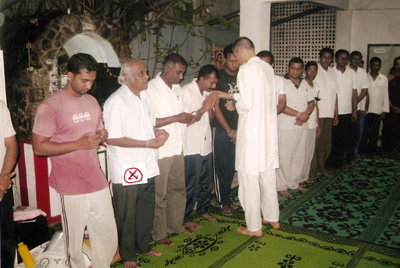 Professor W.M. Gunatilaka (auf dem Bild mit einem roten X markiert), der zwei der Kriya-Yoga-Publikationen in die singhalesische Sprache
                übersetzt hat, empfängt während der Initiierung Prasad von Acharya Satyananda